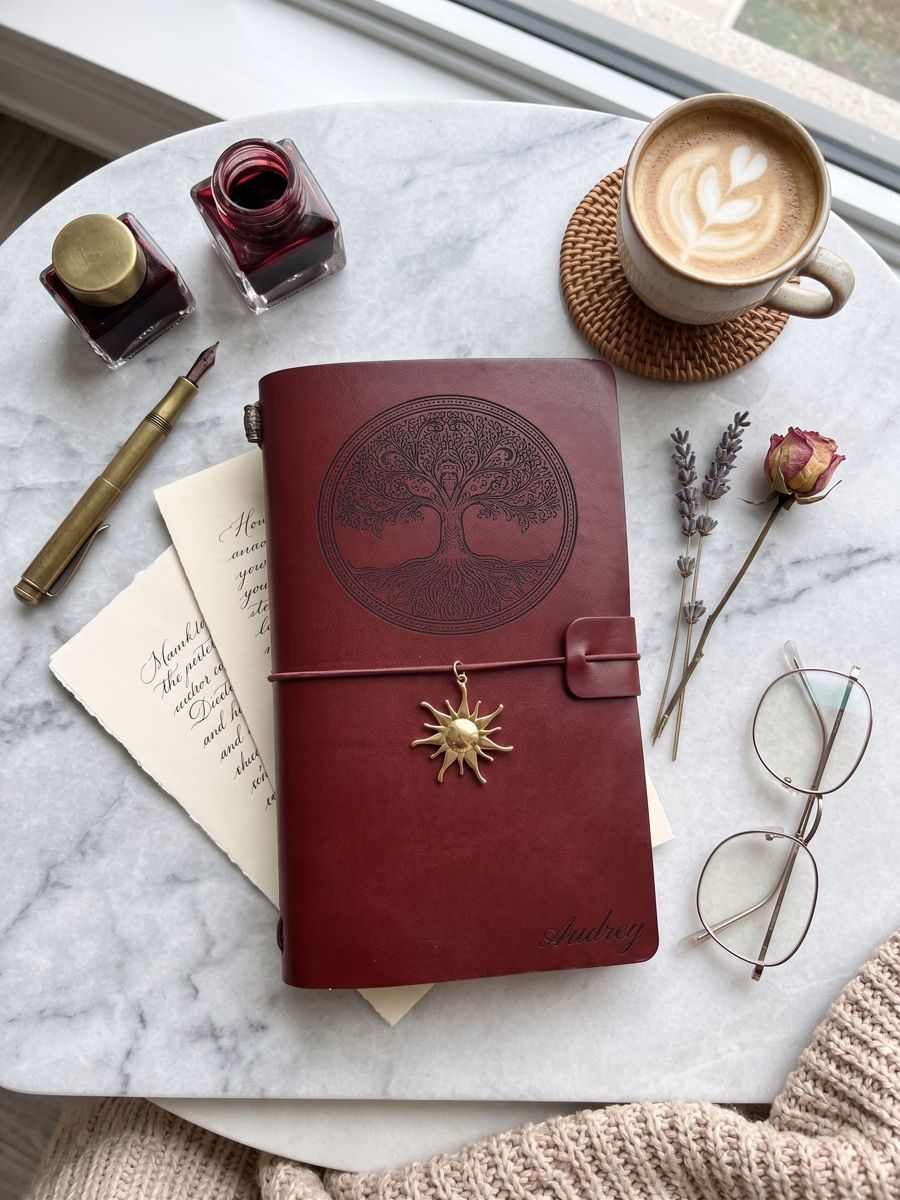 Carnet en cuir vegan bordeaux gravé d'un arbre de vie sur une table en marbre