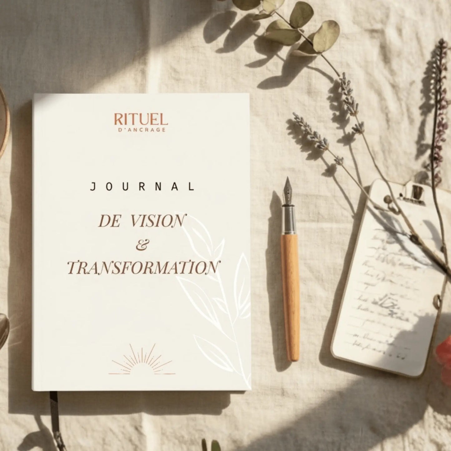 journal de vision transformation blanc posé à plat sur un bureau avec un stylo et une feuille d'olivier